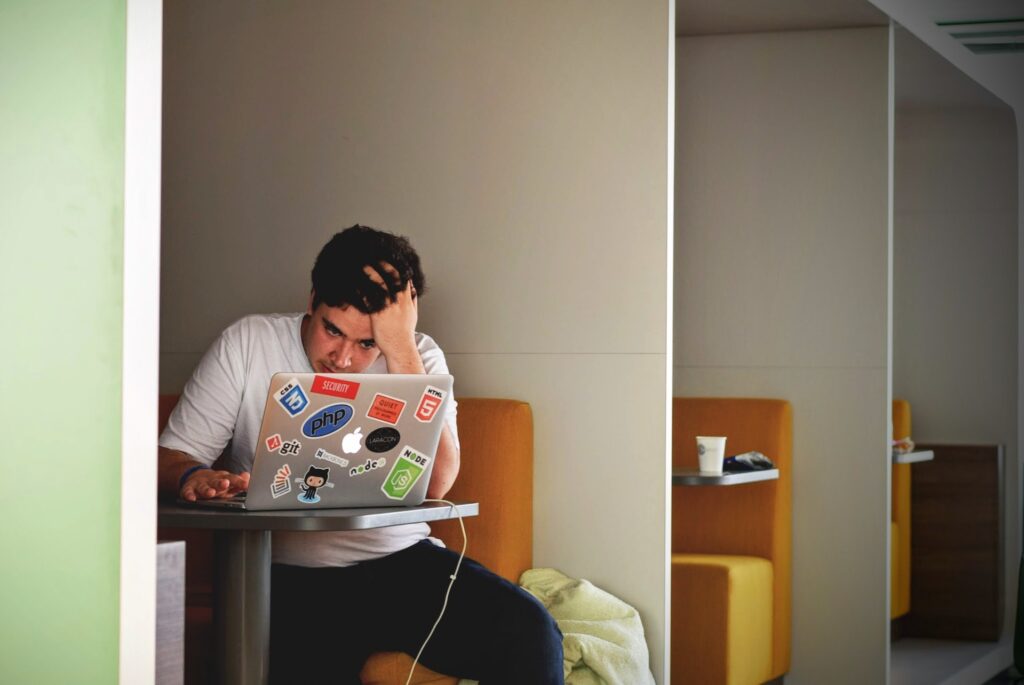 Akademia JA - Mężczyzna siedzący przy stole z laptopem, próbujący poradzić sobie ze stresem.