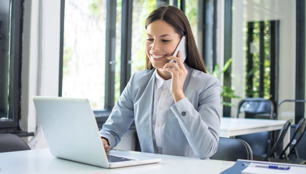 <strong>Akademia JA</strong> - Kobieta biznesu rozmawia przez telefon, siedząc przy biurku, podczas coachingu online w Gdańsku.